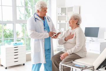 Obraz premium Ill senior woman talking to doctor in clinic