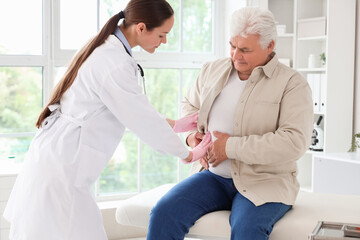 Obraz premium Female doctor examining mature man with bellyache in clinic