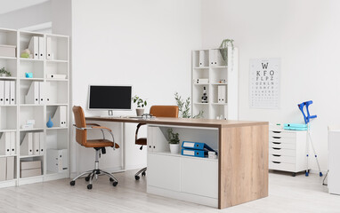 Interior of medical office with doctor's workplace, shelf units and eye test chart