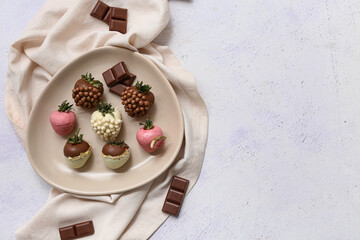 Plate with chocolate covered strawberries on white background
