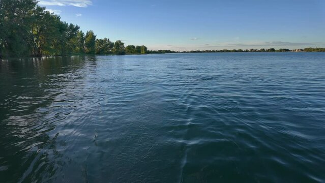 Lake view and wake behind a stern of recreational rowing shell, rower POV perspective, springtime on Boyd Lake in Colorado