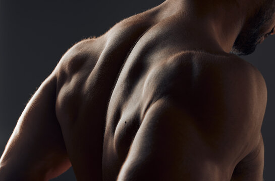 Closeup, muscle and back of man for exercise with workout, gym aesthetic and results for fitness goals in studio. Topless guy, bodybuilder and sexy body with shoulder training by black background