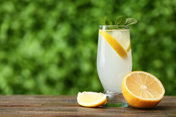 Fototapeta premium Glass of fresh lemonade with mint on wooden table outdoors