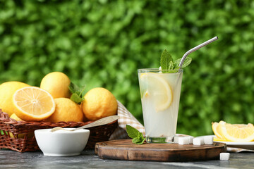 Glass of fresh lemonade with mint and sugar on black table outdoors