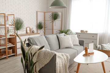 Interior of living room with sofa, folding screen and plants