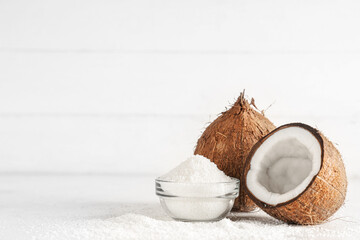 Fresh coconuts and glass bowl with flakes on white table