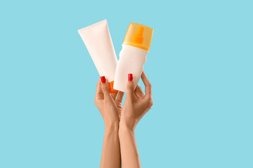 Female hands with sunscreen cream on blue background
