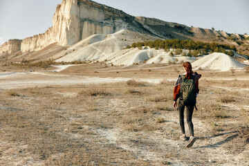 solitary hiker trekking through arid desert landscape with towering mountain peak in the distance