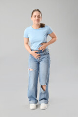 Young woman suffering from menstrual pain on light background