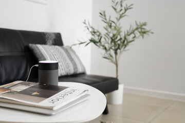 Air humidifier with magazines on table in living room, closeup