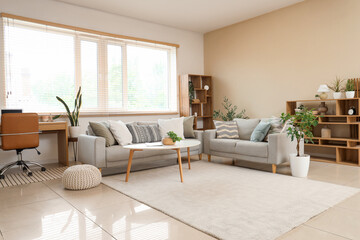 Interior of living room with grey sofas, workplace and plants