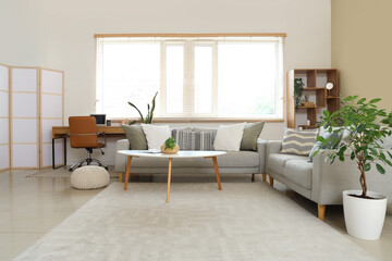 Interior of living room with grey sofas, workplace and plants