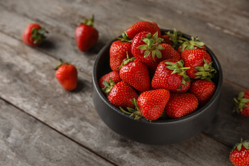Bowl with sweet fresh strawberries on wooden background