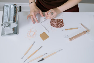 A woman is making a paper craft on a table with various tools and materials