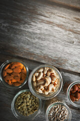 Nuts, cashew and almond on table, above and mockup space for nutrition, health or promotion for wellness. Hazelnut, sunflower and pumpkin seeds in glass container for meal prep with food at apartment