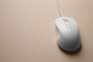 One wired mouse on beige background, closeup. Space for text