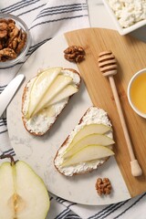 Delicious ricotta bruschettas with pear and walnut on white table, flat lay