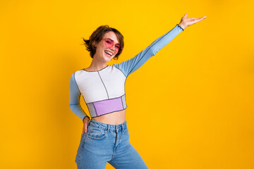 Photo of funky excited lady dressed shirt heart shape eyewear showing arm empty space isolated...