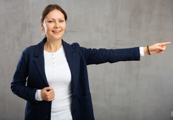 Smiling adult woman dressed in jacket gesturing in studio