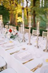 Set table with invitations on plates among lit candles in the garden