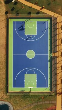 Vertical Screen: On a tall vertical screen, theres a lively and modern basketball court in a park, highlighting the recreational vibe of the setting with urban features and vibrant colors