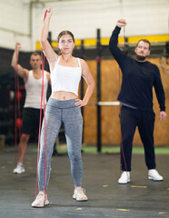 Determined young girl working out with resistance band in well-equipped gym during training session