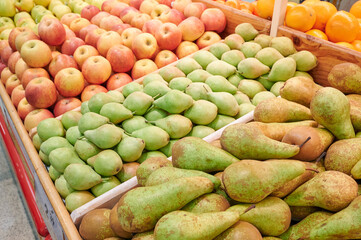 Shopping at the greengrocer. Sections with different types of pears and apples in the supermarket's fresh fruit section