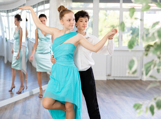 Dance teacher teaches a girl and boy couples ballroom dancing