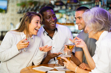 View on the young Interracial couple talking to diversse group at a bar
