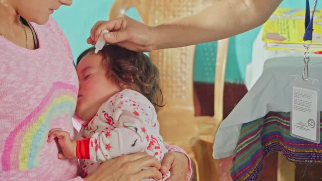 Nurse administers drinkable dose of vaccine to Latina girl.