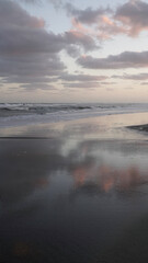 Enchanting view of the sea shore under a magical sunset sky.  The sky reflects in the wet sand.