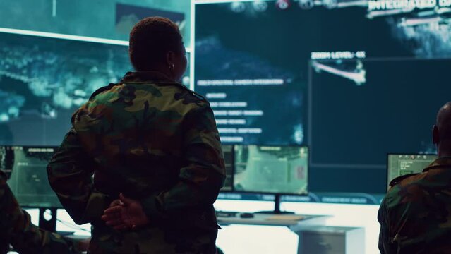 Female technical sergeant monitoring air traffic to detect any enemy aircraft, working in federal reconnaissance system to ensure national safety. Woman officer uses big screen and gear. Camera A.