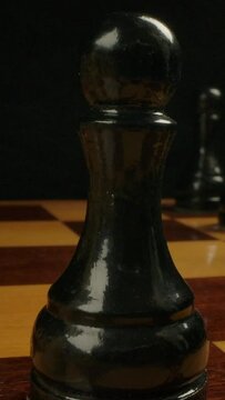 Chess player nominates black central pawn on e5 from e7. Extremely close-up shot of pawn chess piece on checkerboard, wide-angle view of chess game. Vertical shot.
