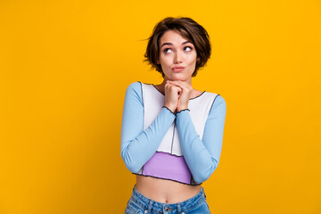 Photo of doubtful unsure lady dressed shirt arms chin looking empty space isolated yellow color...