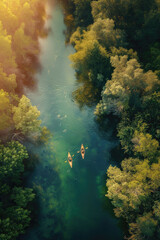 Fototapeta premium Two people in kayaks are paddling down a river surrounded by trees