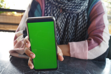 A person using smartphone with green screen, showcasing modern technology and digital interaction