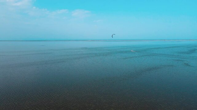 An aerial view of a body of water with a person windsurfing and parasailing , kite surfing in the ocean of Djerba Lagune at Tunisia