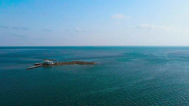 An aerial view of el biben island with a pool and hosting houses sits in the middle of the ocean with palm trees on it, surrounded by water creating a beautiful atmosphere. from Zarzis at Tunisia
