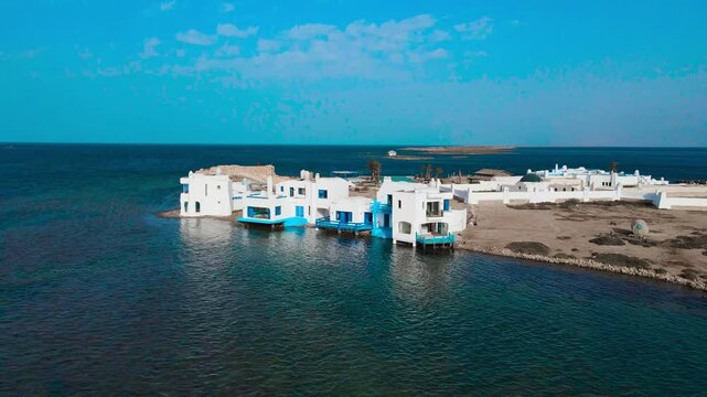 An aerial view of el biben island with a pool and hosting houses sits in the middle of the ocean with palm trees on it, surrounded by water creating a beautiful atmosphere. from Zarzis at Tunisia