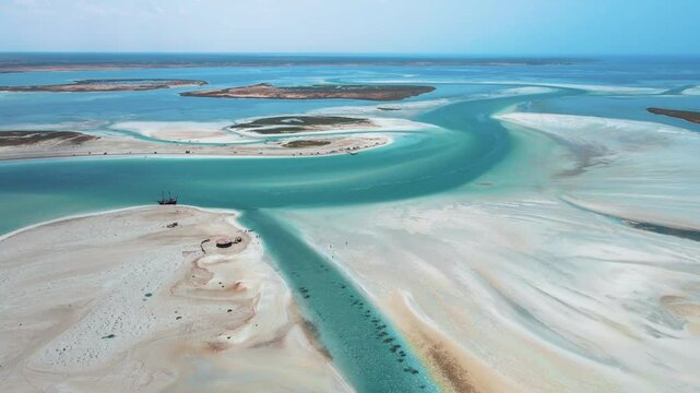 An aerial view of Hassi El Jerbi aquatic beach scene with people and boats in the water at Zarzis Tunisia. People are walking on the beach, enjoying their time near the water.