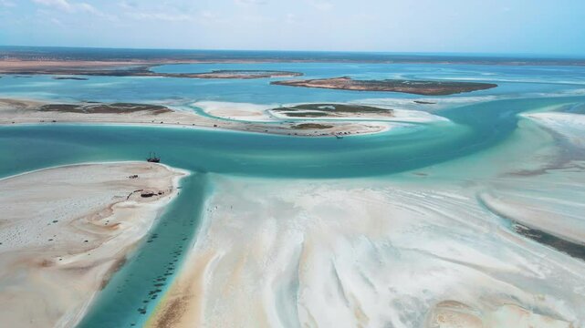 An aerial view of Hassi El Jerbi aquatic beach scene with people and boats in the water at Zarzis Tunisia. People are walking on the beach, enjoying their time near the water with rivers surrounding