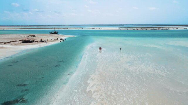 An aerial view of Hassi El Jerbi aquatic beach scene with people and boats in the water at Zarzis Tunisia. People are walking on the beach, enjoying their time near the water.