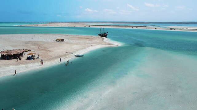 An aerial view of Hassi El Jerbi aquatic beach scene with people and boats in the water at Zarzis Tunisia. People are walking on the beach, enjoying their time near the water.