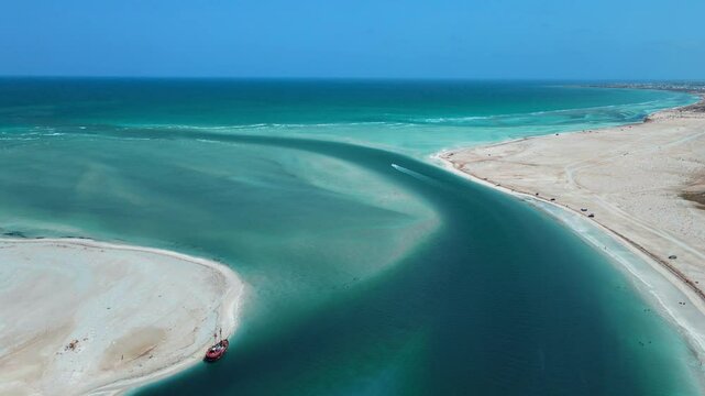 An aerial view of Hassi El Jerbi aquatic beach scene with people and boats in the water at Zarzis Tunisia. People are walking on the beach, enjoying their time near the water.