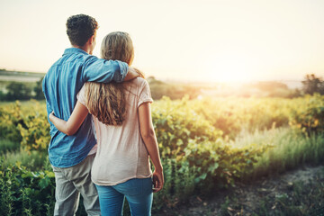 Back, hug and couple in sunrise, outdoor and together with care, love and date for anniversary in park. Morning, partner and person with embrace, nature and peace in field and relax in Texas in farm