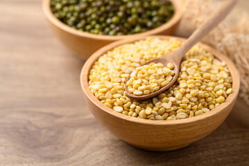 Obraz premium Yellow peeled split mung bean in bowl with spoon on wooden background, Food ingredient