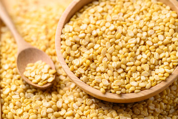 Yellow peeled split mung bean in wooden bowl with spoon, Food ingredient