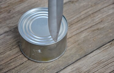 sharp knife and canned food on a wooden table. open canned food with a knife. food on a hike