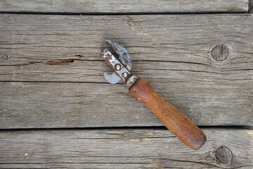 can-opener. old rusty canning knife with a wooden handle on a wooden background. top view