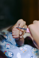 A mother cutting her daughter's nail on finger hand